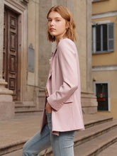 A lady wears a pink blazer.